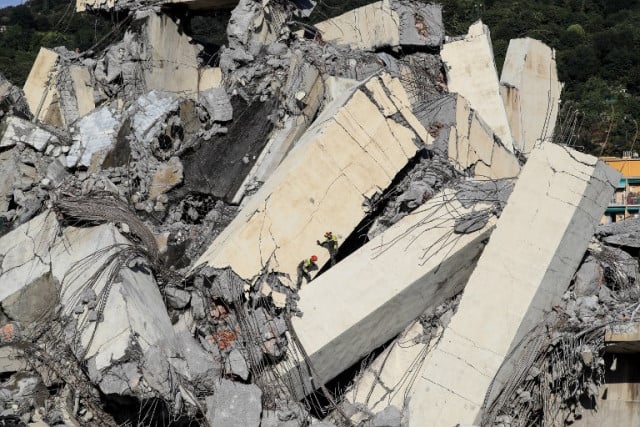 Italian rescuers climb onto the rubble of the collapsed Morandi motorway bridge searching for victims and survivors in the northern port city of Genoa on August 14, 2018. Photo: Valery Hache / AFP